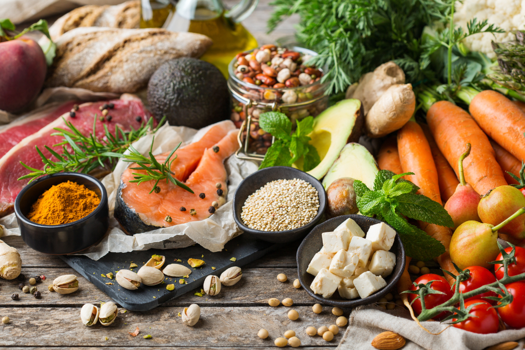 Variety of immune-boosting foods including salmon, vegetables, whole grains, nuts, herbs, and spices to boost immune system naturally