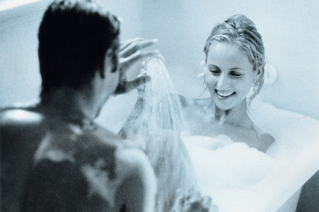 Couple sharing intimate playful moment together in bathtub representing daily intimacy and emotional connection