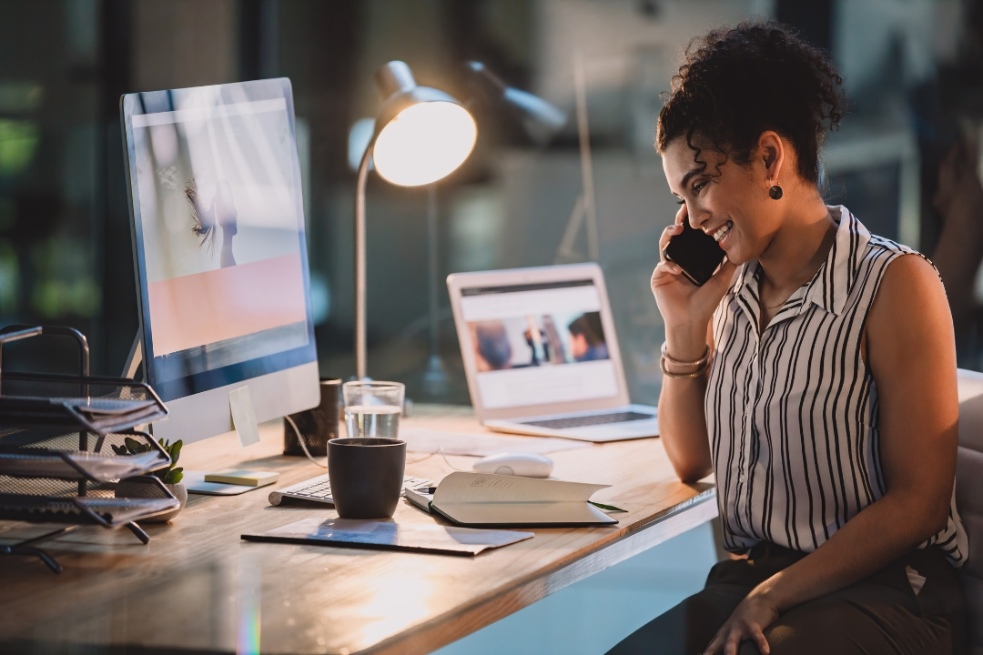 Professional woman working on side hustles at organized home office desk with phone and computer