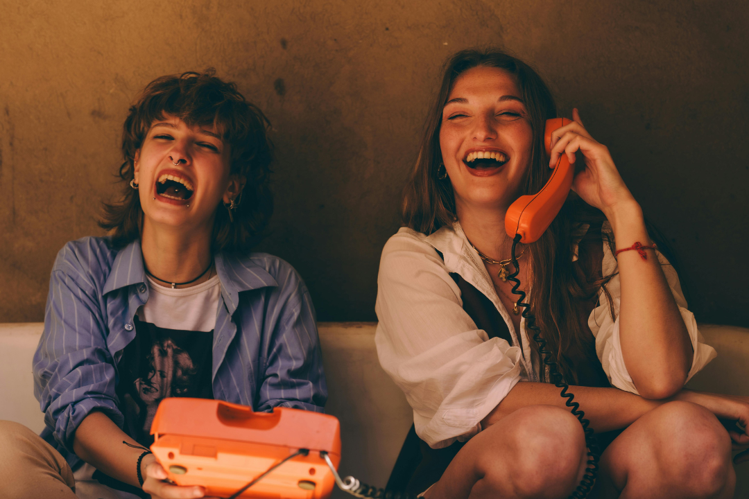 5 Everyday Habits That Genuinely Support Your Mental Health Two friends laughing together on couch with retro phone showing social connection habits that support mental health